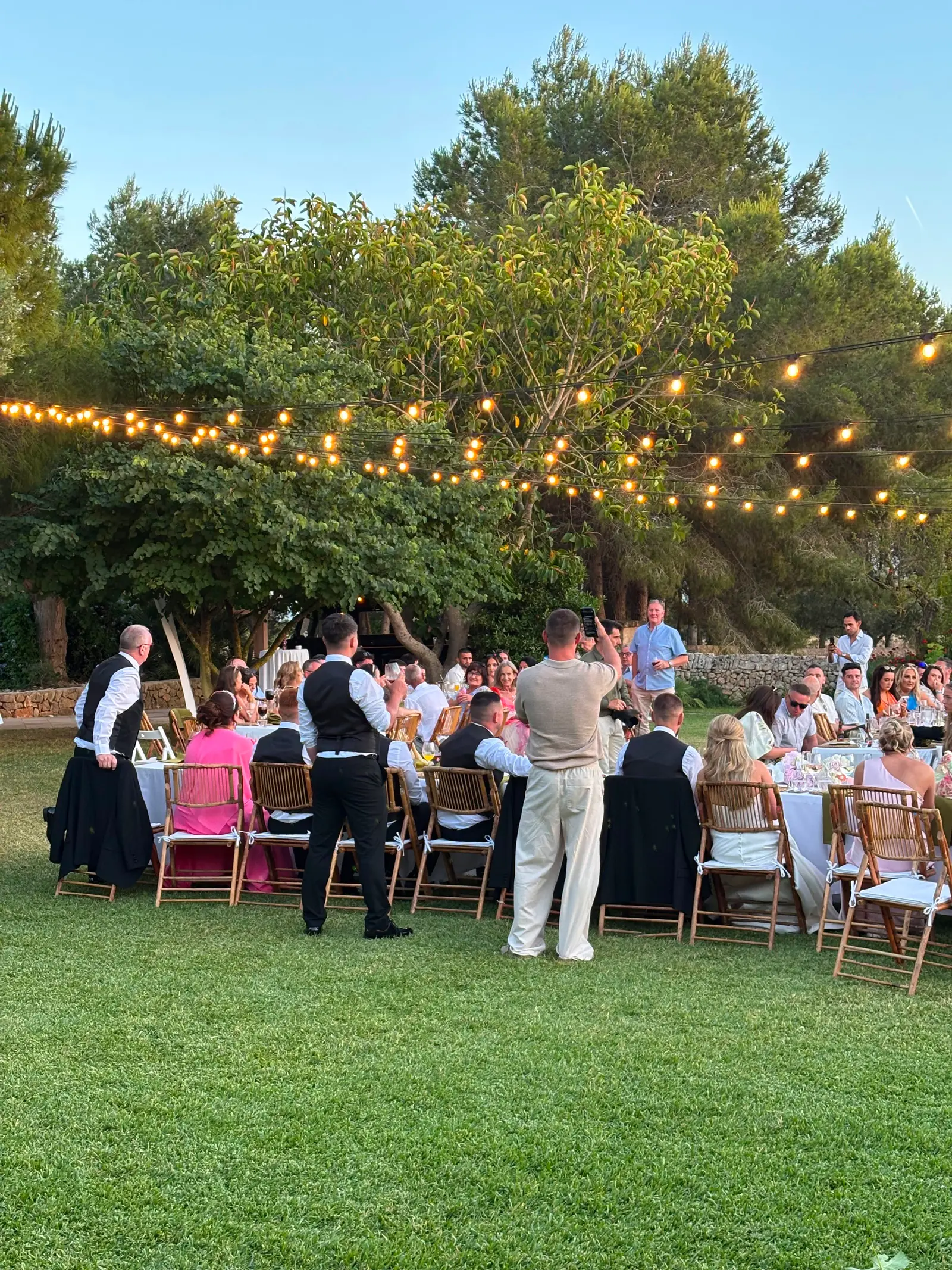 Cena privada en un jardín iluminado con guirnaldas