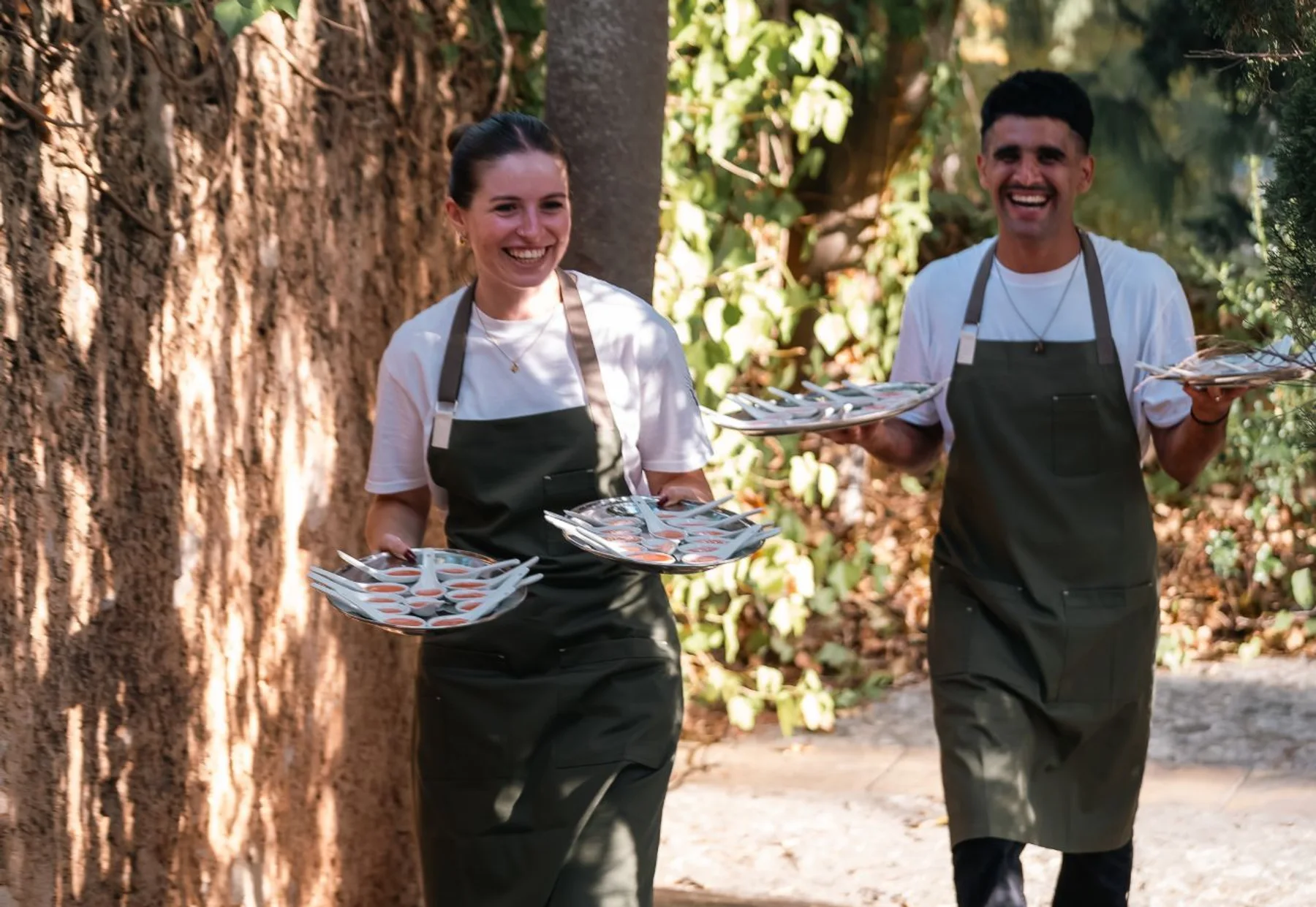 Dos camareros de Grupo Picolín sonriendo con bandejas de aperitivos en una finca
