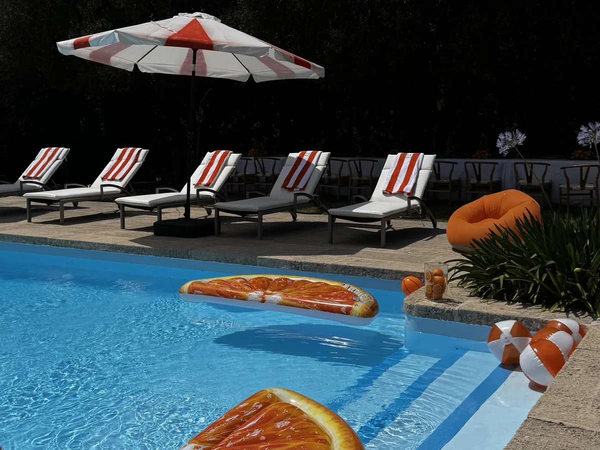 Poolparty in einer Villa mit orangefarbenen Schwimmringen und gestreiften Liegen