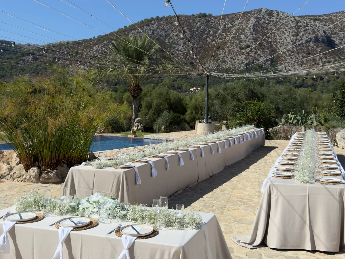 Hochzeitstische am Pool einer Villa, im Hintergrund die Berge