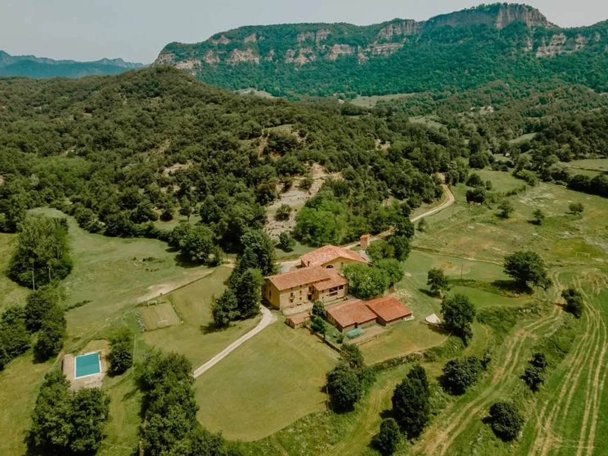 Luftaufnahme einer Masia, eines katalanischen Landguts inmitten von Wäldern und Bergen, vorbereitet für ein Firmen-Retreat