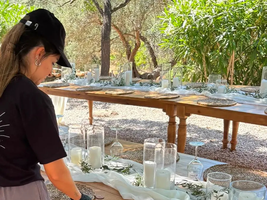 Auxiliar preparando copas en una mesa exterior