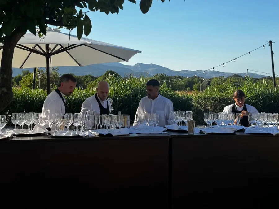Equipo de bartenders preparando la barra al aire libre en una finca, con la sierra al fondo