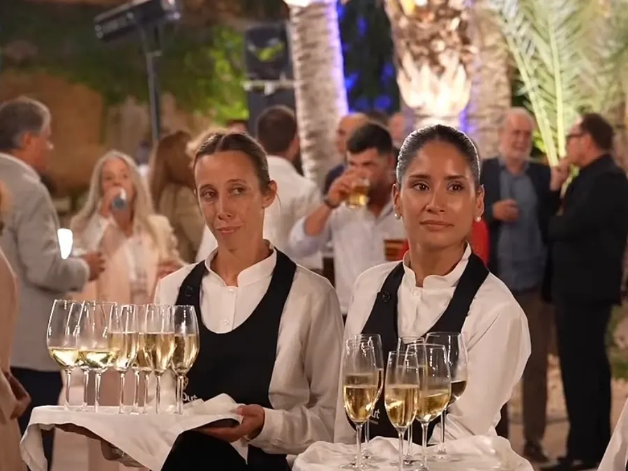Dos camareras con bandejas de cava en un cóctel nocturno