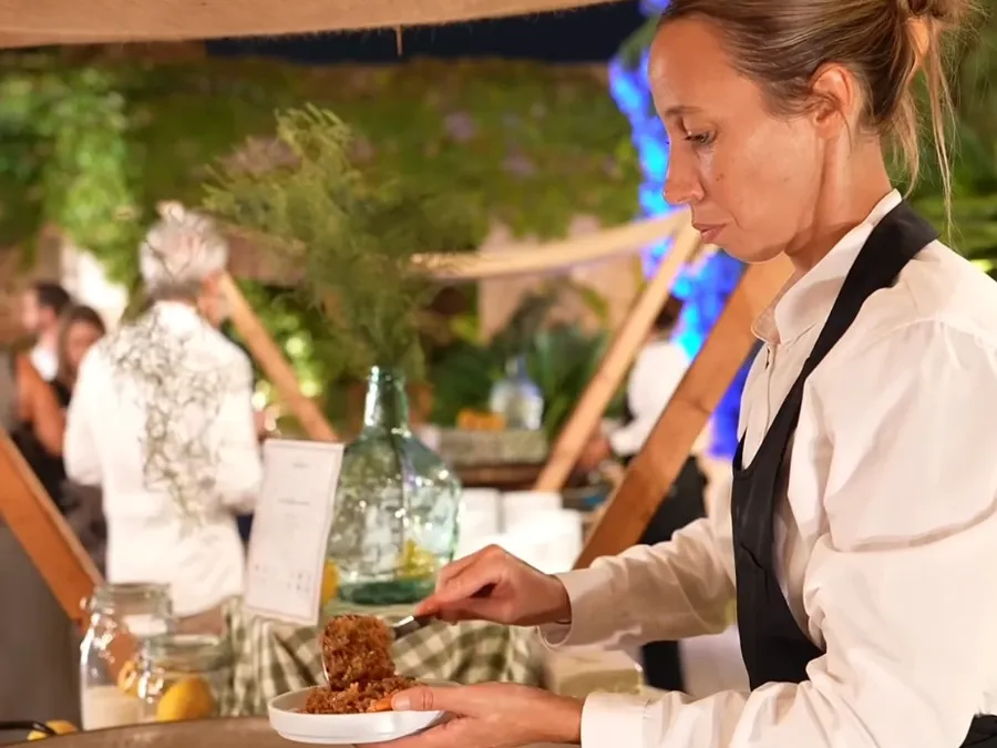 Ayudante de cocina sirviendo arroz de la paella en un evento nocturno