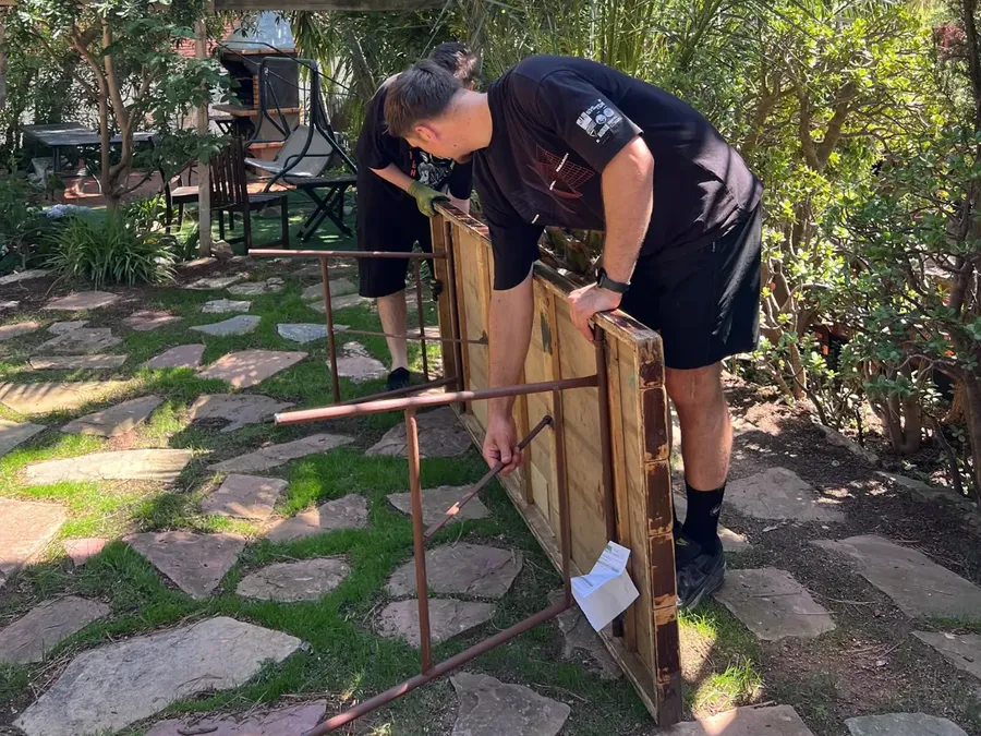 Dos montadores de Grupo Picolín montando mesas en el jardín de una casa